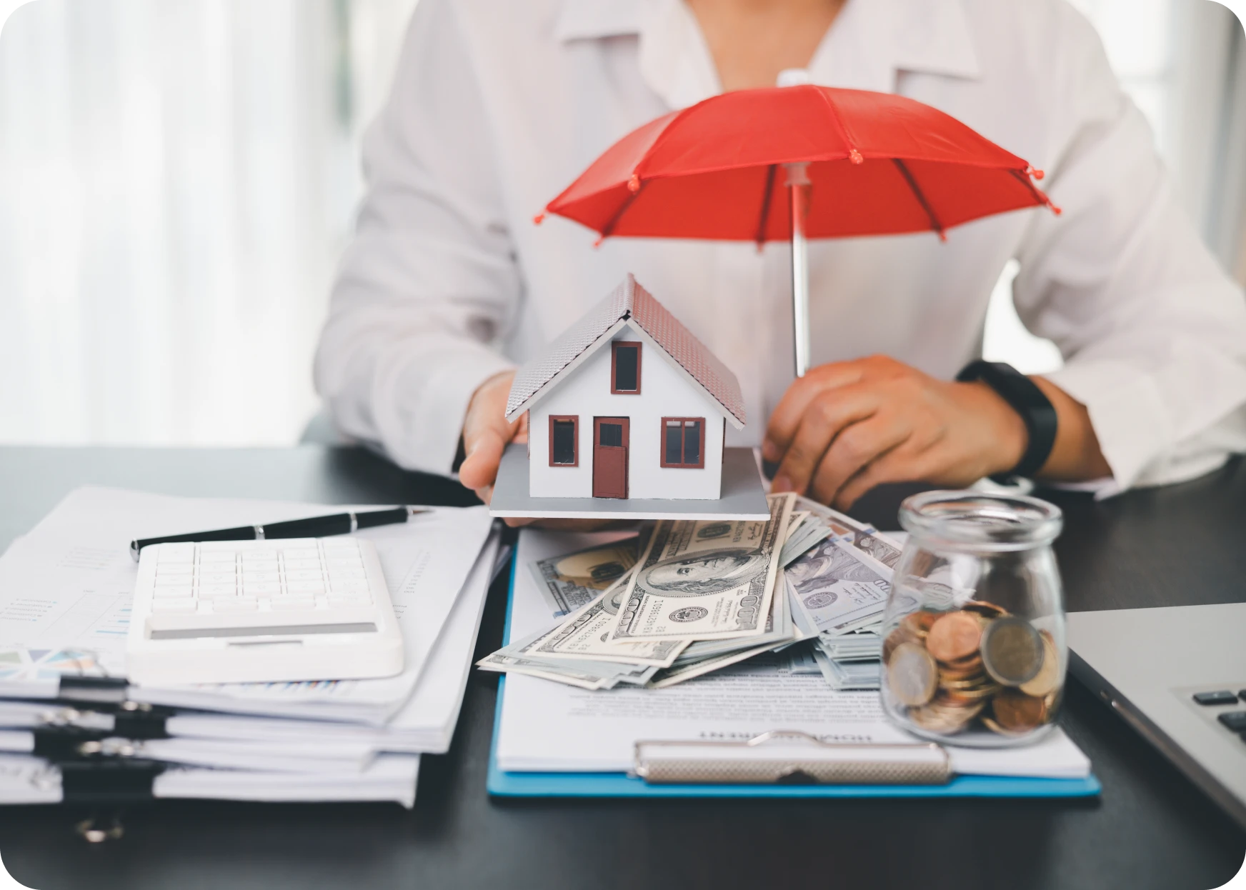 Person with house, umbrella protection, and documents representing home insurance and financial coverage security