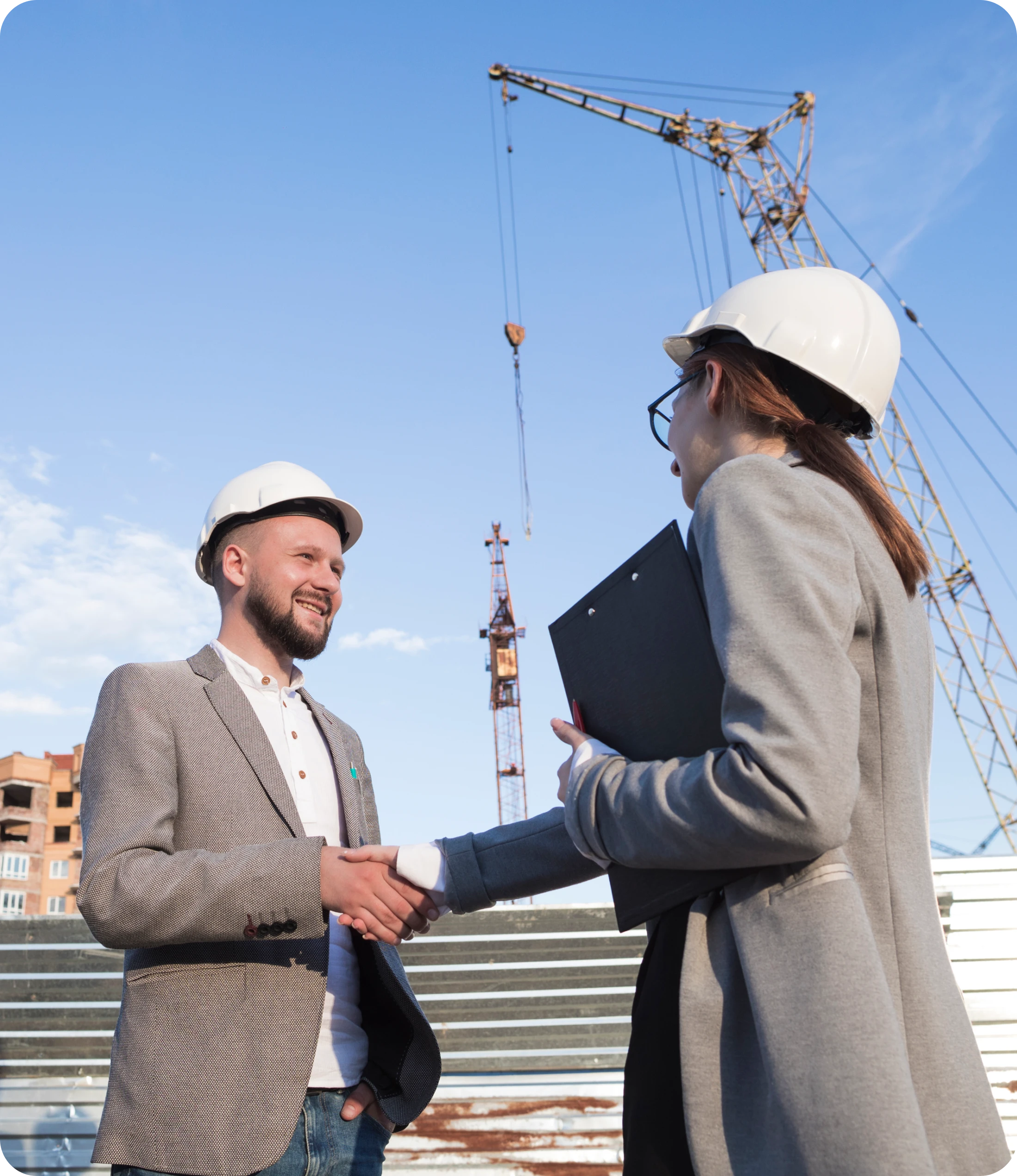 Man In White Hard Hat Shaking Hands With Woman Holding Clipboard